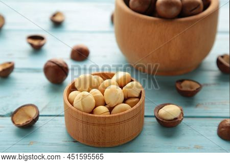 Macadamia Nuts On Wooden Bowl On Blue Background.