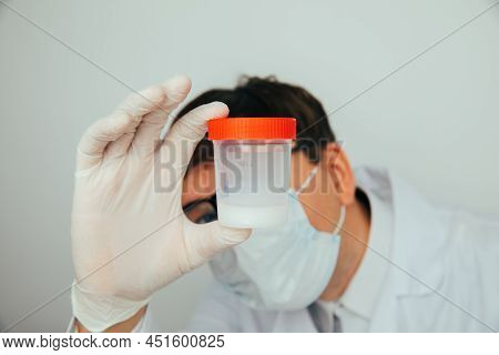 The Doctor Looks At The Plastic Jar With Sperm For Semen Analysis. Medacine, Pills, Medicine, Vitami