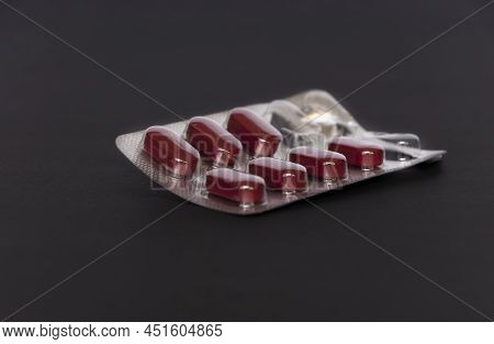 Closeup Image Of Ayurvdic Red Color Tablet In Black Background. Selective Focus