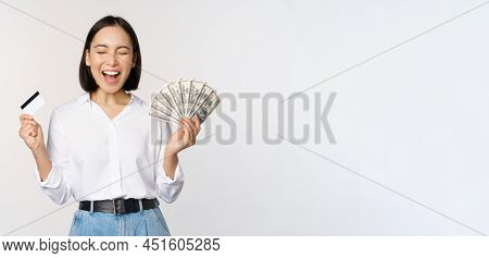 Finance And Money Concept. Happy Young Asian Woman Dancing With Cash And Credit Card, Smiling Please