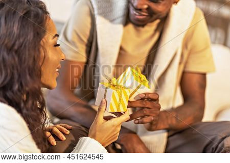 A Happy Couple Of Mulattoes Exchange Gifts With Each Other. Celebrating Joint Family Events