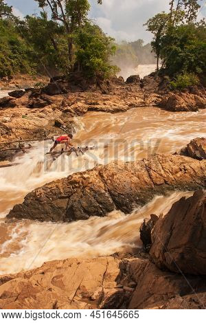 Laotian Fisherman Fishing On Rapids Of The Khone Phapheng Falls On The Mekong River In Rainy Season.