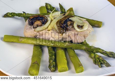 Porkl Chop With Sauteed Onions And Mushroom Resting On Asparagus