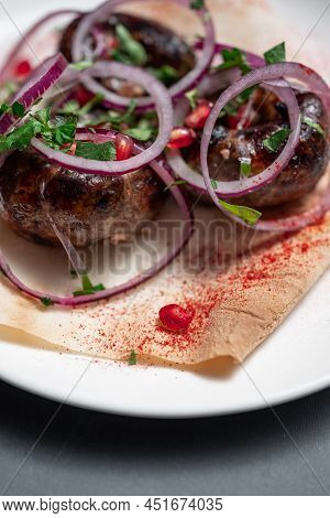 Georgian Fried Pork Sausages Kupaty With Onion, Cilantro On Pita On White Plate