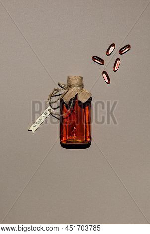 Transparent Container Filled With Algae Based Oil And Few Jelatin Oil Capsules. Glass Bottle Is Tied