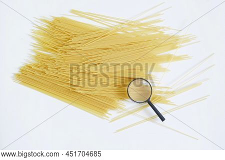 Magnifying Glass And Quality Durum Wheat Spaghetti On A White Background. Concept Of Analysis And Ex