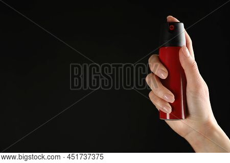 Woman Holding Pepper Spray On Black Background, Closeup. Space For Text