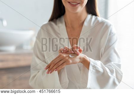 Skincare Concept. Closeup Of Young Woman Rubbing Moisturising Cream On Hands
