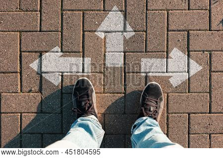 Person Stands On The Road, Choosing The Direction Of The Path. Arrows On The Ground. Top View, Fit C