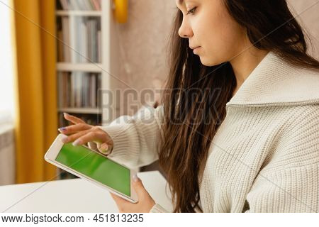 A Girl Works At Home At A Dask With A Laptop And Smiles.