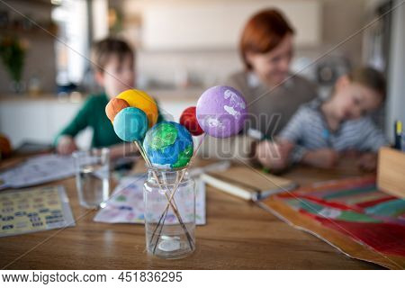 Mother Of Little Children Supervising Them When Diong Homework At Home.