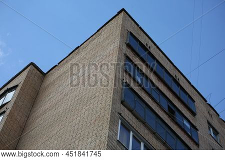 Brown Brick House. A Corner Of A Soviet High-rise Building, Taken From Below Against A Blue Backgrou