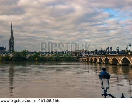 Stone Bridge On The Garonne River In Bordeaux With St Michel Cathedral, France.