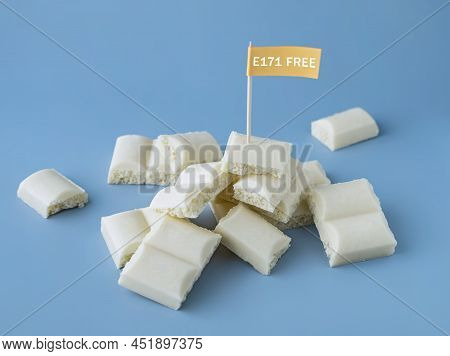 Heap Of White Chocolate Cubes With The Sign Of A Dangerous Additive E171 On A Blue Background