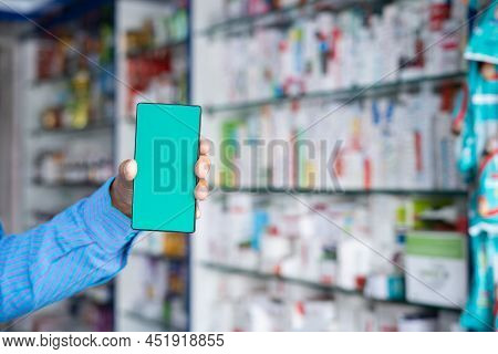 Close Up Shot Of Hands Holding Green Screen Mobile Phone At Retail Pharma Store In Front Medicine Bo