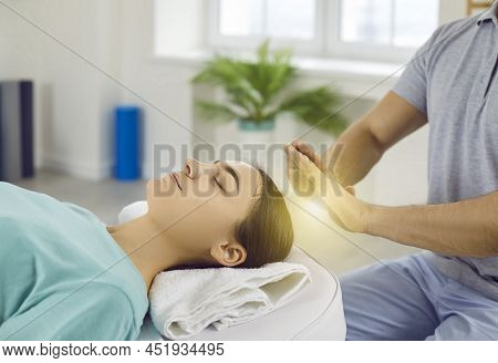 Woman Relaxing And Restoring Energy During Holistic Healing Session With Reiki Therapist