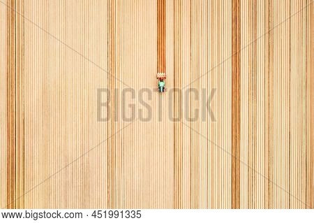 Lonely tractor on agricultural field with rows of plowed soil. Agricultural fields prepared for planting crops, topdown view. Industrial agriculture concept. Drone photography