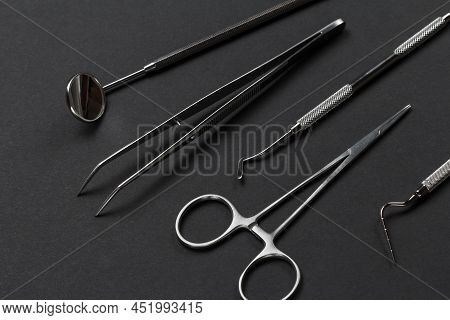 Set Of Metal Instruments For Dental Treatment. Mouth Mirror, Tweezers, A Dental Restoration Instrume