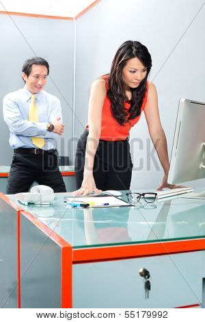 Asian Employee or secretary getting being sexually harassed by her boss or manager, he is looking her at the backside while she is working 