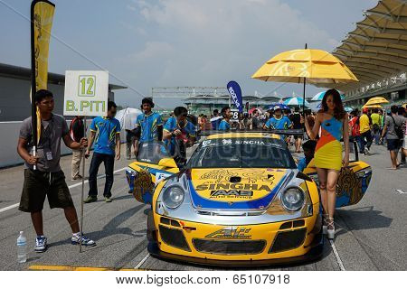 SEPANG, MALAYSIA - MAY 11, 2014: The Singha Porsche AAS Team grid girl poses with the team car, a Porsche 997 at the start grid of the Thailand Supercar Race in Sepang International Circuit.