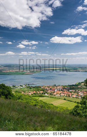 Spring Countryside With Village, Lake, Blue Sky And Clouds