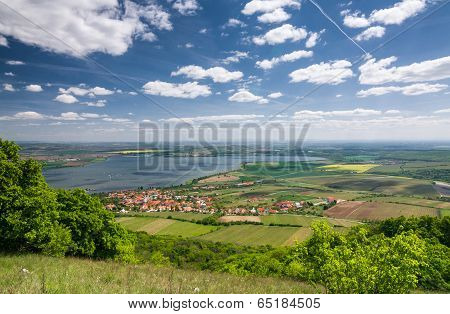 Spring Countryside With Village, Lake, Blue Sky And Clouds