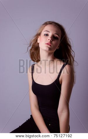 young, beautiful girl in a black t-shirt. Professional model posing in Studio on white-gray