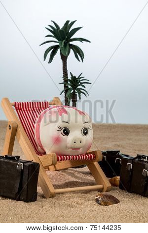 a piggy bank is in a deck chair. symbol photo for airline travel and expenses on vacation