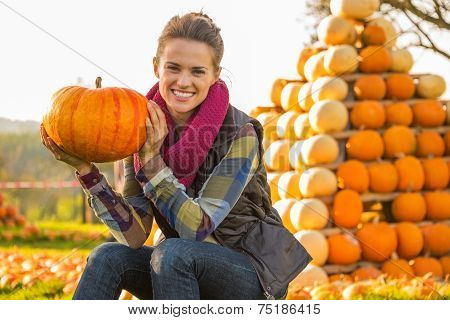 Portrait Of Happy Young Woman Sitting With Pumpkin In Front Of P