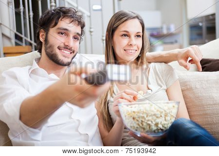 Couple using a remote control while sitting on the couch