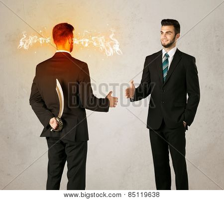Angry businessman hiding a weapon behind his back 