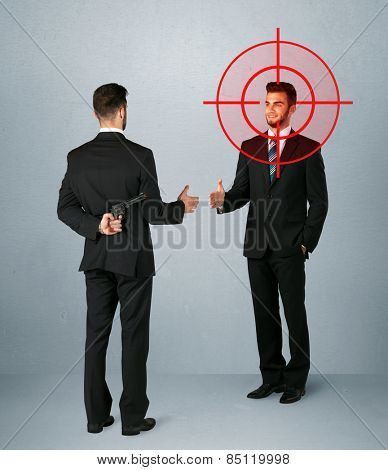 Ruthless businessman handshake with a hiding weapon and a head target point 