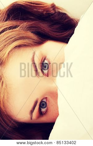 Young woman looking scared in bed.