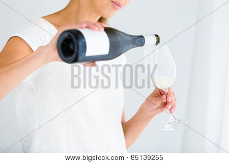 Gorgeous young woman with a glass of wine, pouring herself a glass of wine (shallow DOF; color toned image)