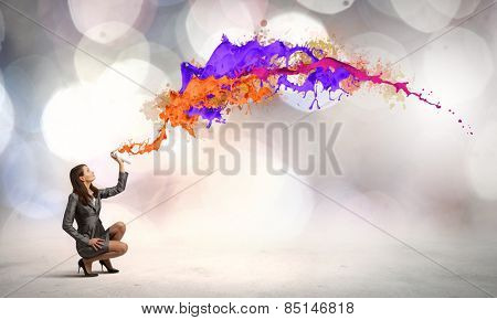 Businesswoman spraying colorful paint splashes from container