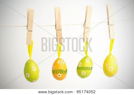 bona pascua against four easter eggs hanging from a line