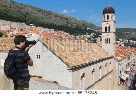 DUBROVNIK, CROATIA - MAY 26, 2014: Young photographer taking photos of Stradun from Old city walls. Stradun is 300 meters long main pedestrian street in Dubrovnik.