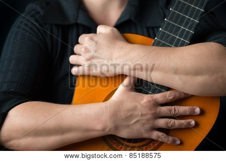Classic guitar closeup - Musician hands embracing a classic acoustic guitar