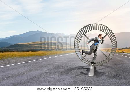 Young businessman running in huge hamster wheel