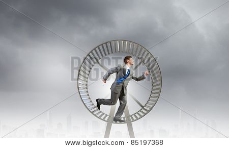 Young businessman running in huge hamster wheel