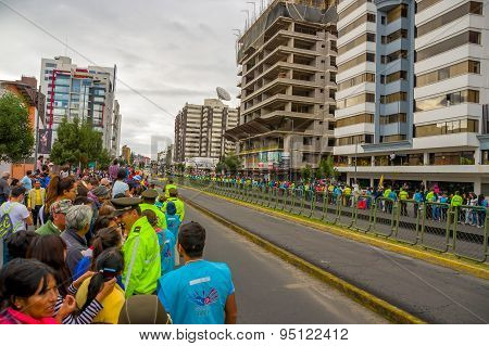 Crowds of people in Quito city street waiting for Pope Francis motorcade to arrive as numerous polic