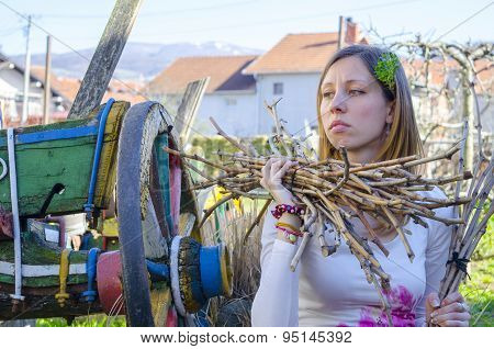 Sad Farm Girl Holding Wooden Wite In A Backyard With An Old Coloured Wagon In Background