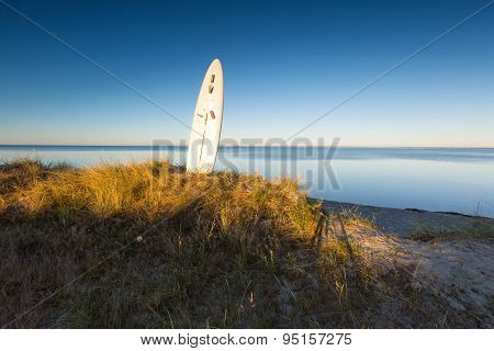 Surfing Board Pounded In Sand On Sea Shore