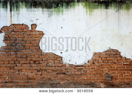 Intonaco bianco macchiato e muro di mattoni