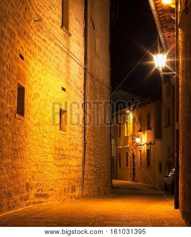 Night narrow street of the old town lit by a streetlamp.