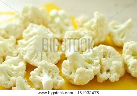 Chopped Pieces Of Cauliflower On Yellow Cutting Board