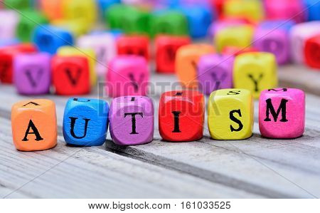 Autism word on grey wooden table closeup