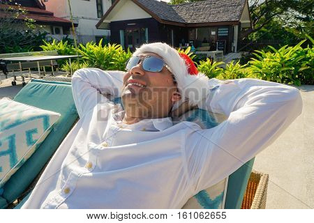Man in Santa Claus Hat Relaxes by the Pool shot with a Sony a6300