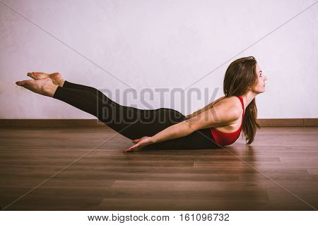 Young pretty woman in black leotard practicing yoga