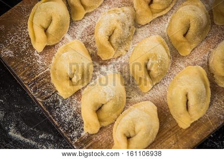 Freshly Prepared Italian Tortellini On Wooden Board  Top View